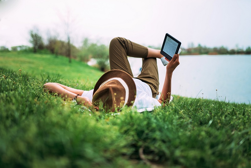 a person reading a tablet on a grassy lawn