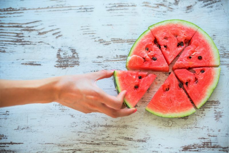 a woman grabbing a sliced watermelon