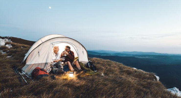 a couple camping on a grassy steppe, overlooking mountains