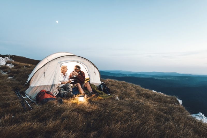 a couple camping on a grassy steppe, overlooking mountains