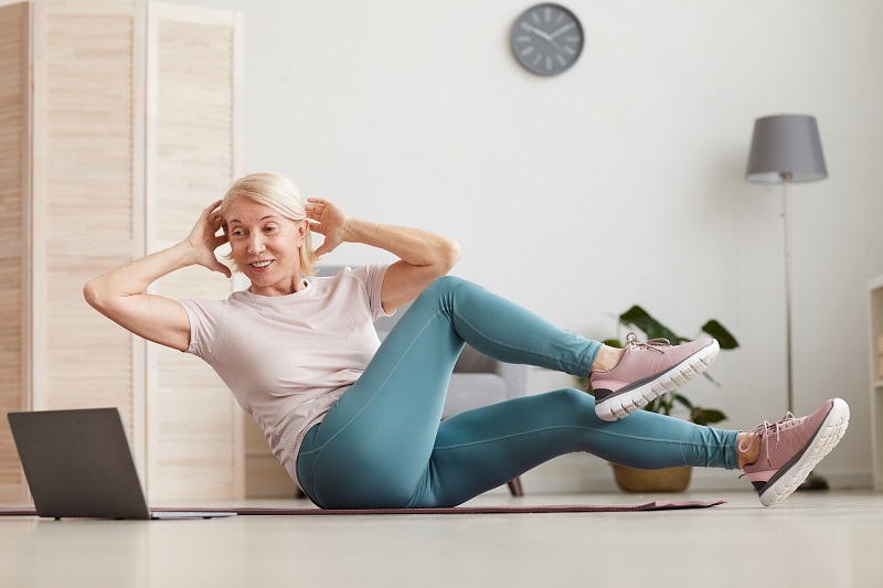 a woman exercising on a yoga mat in front of a laptop for stress relief