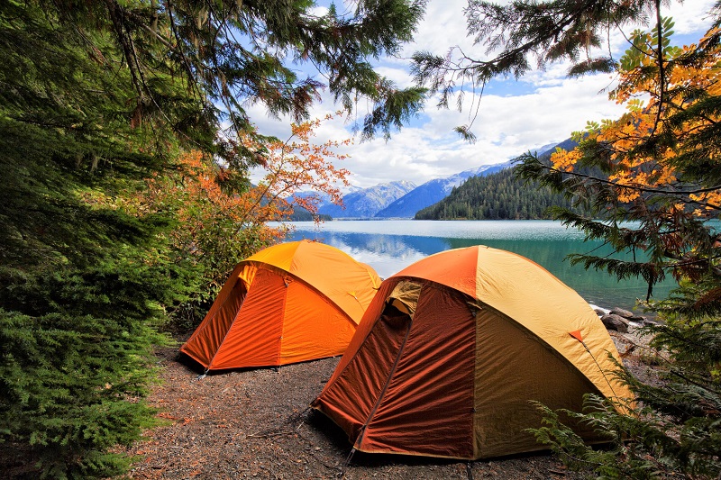 two tents in a remote location facing a lake and mountains