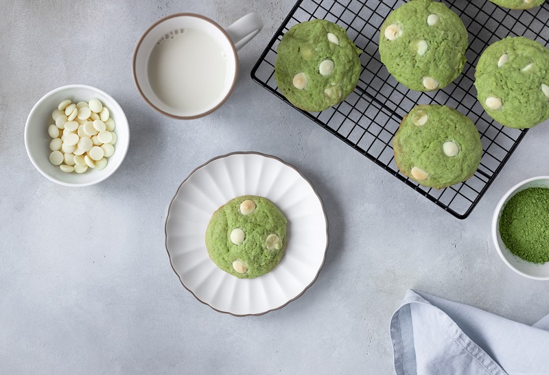 Matcha biscuits with white chocolate on a plate with milk