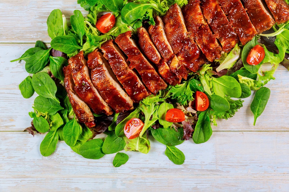 baked baby back ribs on a bed of greens and tomatoes