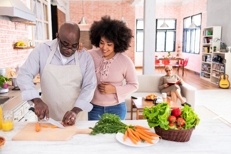 father cutting vegetables with adult daughter