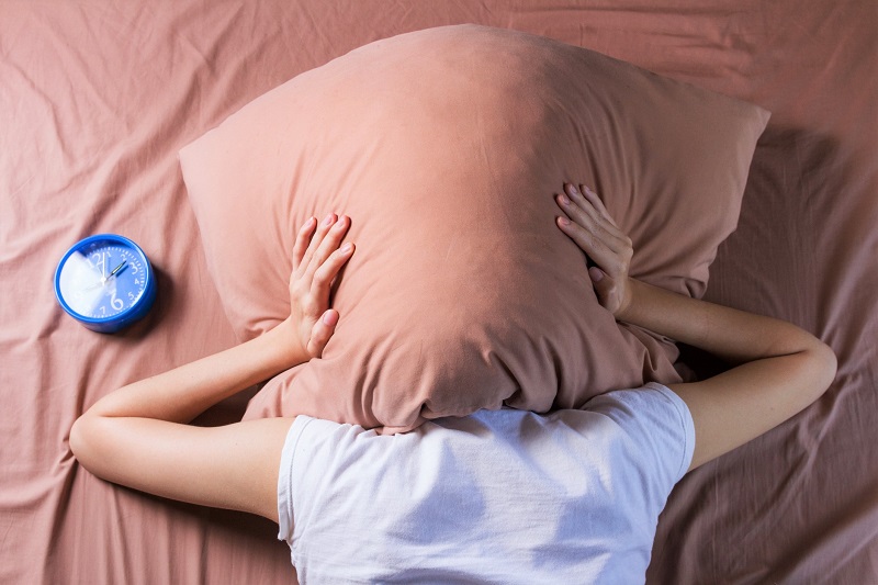 a woman in bed with a pillow over her ears
