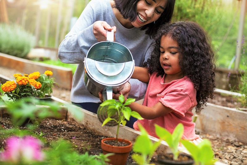 Mother and daughter watering home garden