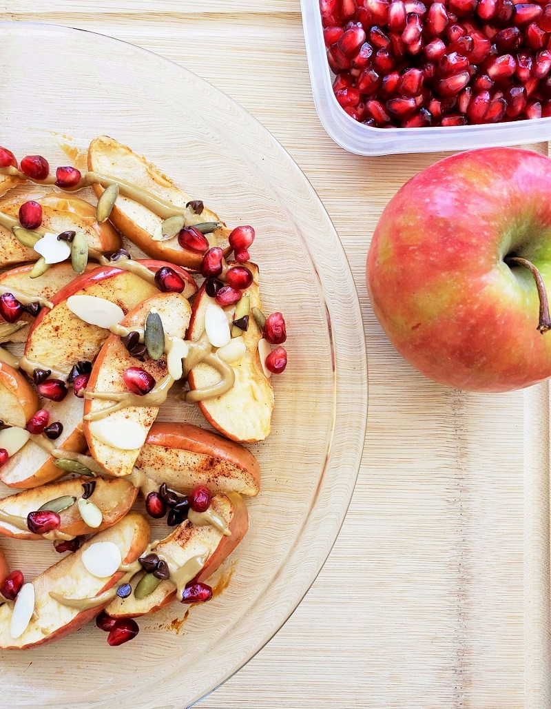 Baked Apple Nachos with nut butter, seeds, chocolate chips and pomegranate seeds