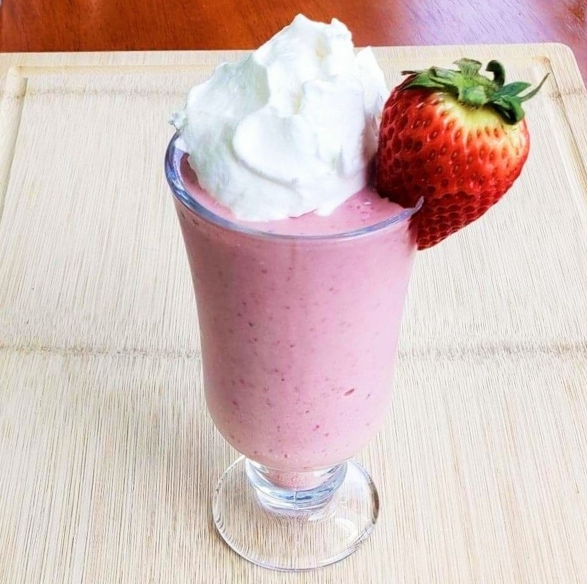 Strawberry Superfood Cheesecake Smoothie with whipped cream and a strawberry garnish