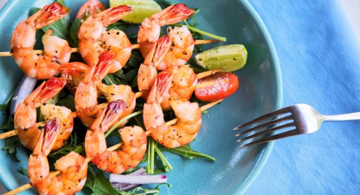 Grilled shrimp skewers with salad and lime slices