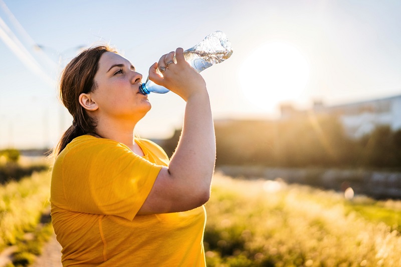 woman drinking water outside in the summer