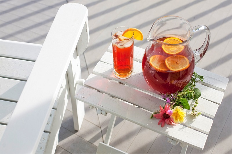 A glass pitcher and glass of iced tea on a sunny porch.