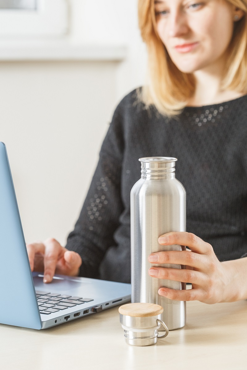 woman holding water bottle while working on laptop