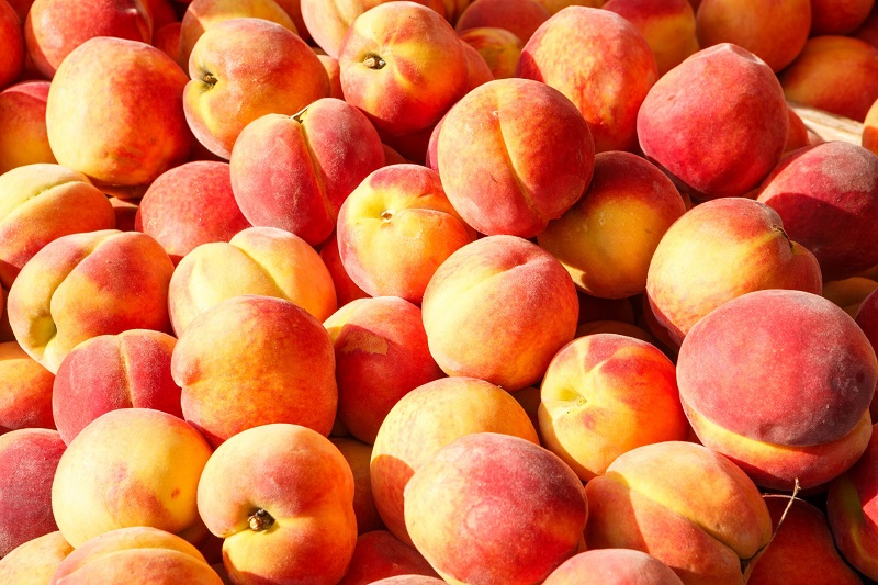 Fresh picked yellow peaches at an outdoor farmer's market