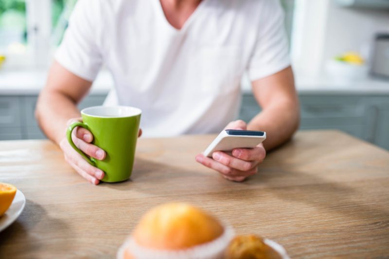 man using the numi app features while drinking coffee at breakfast