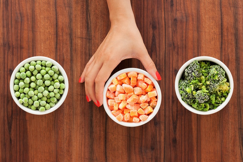 frozen peas, carrots and broccoli in ceramic bowls