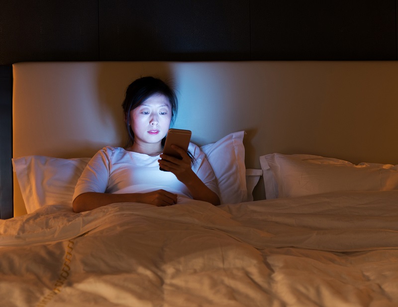 Woman checks her phone in bed before going to sleep