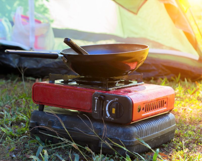 Portable gas camping stove and a frying pan in the camp.