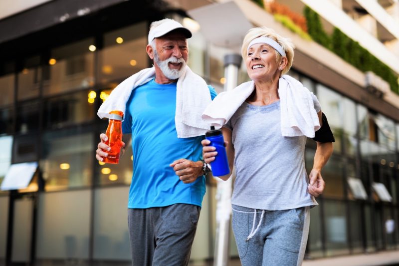 Couple in athletic clothing holding beverages while walking outside