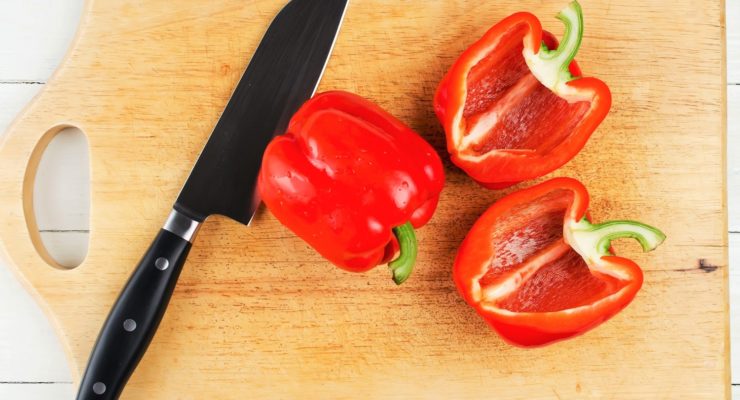 Whole and sliced bell pepper on cutting board