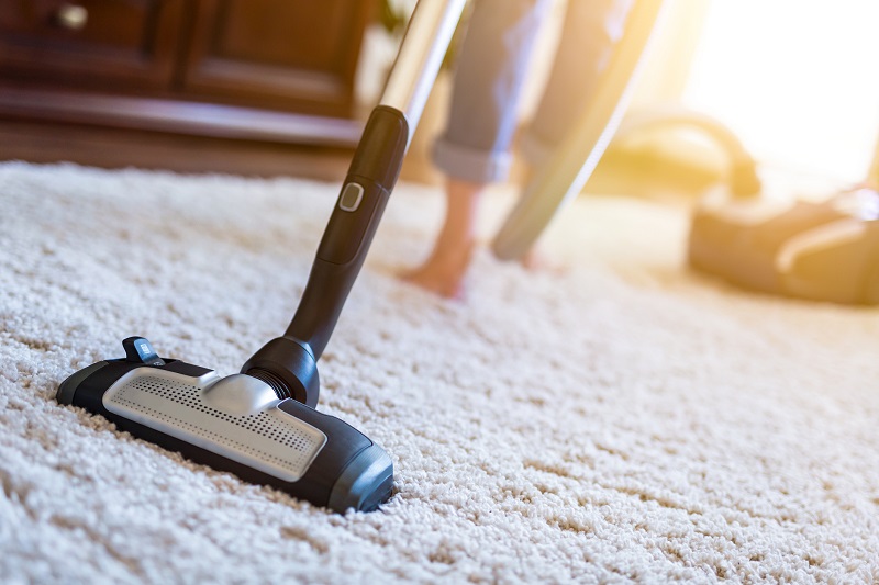 person vacuuming carpet in house and doing cleaning activities
