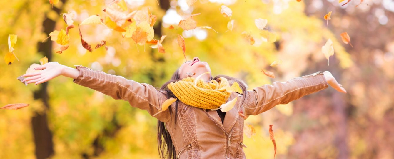 woman throwing leaves in the air during fall