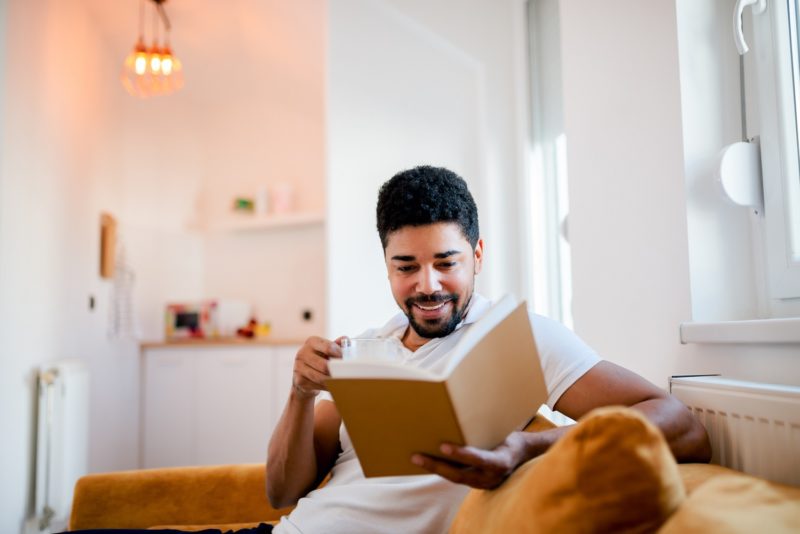 Man smiling as he reads a book near his kitchen