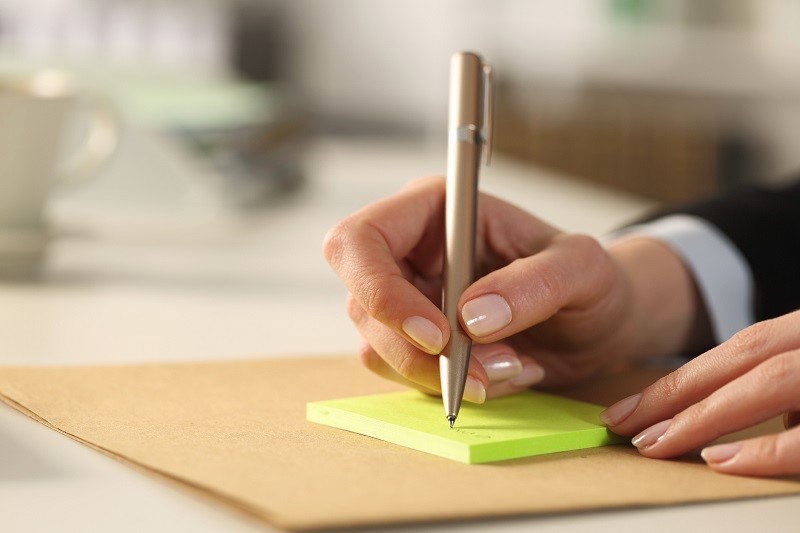 woman writing labels on sticky notes