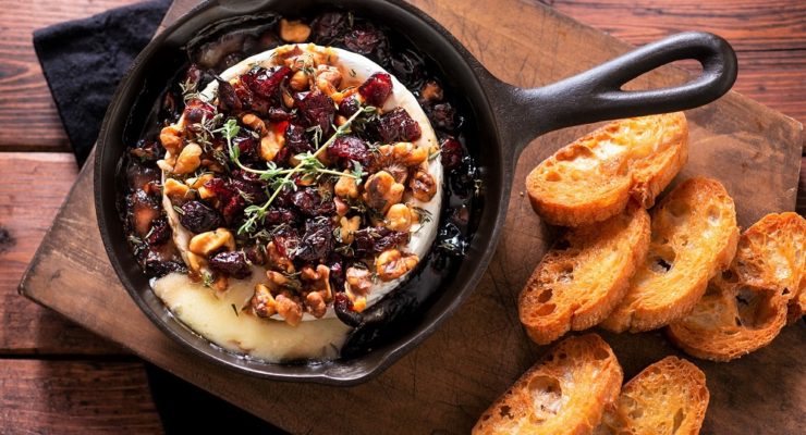 Fruit and nut baked brie in a cast iron pan with bread slices for dipping