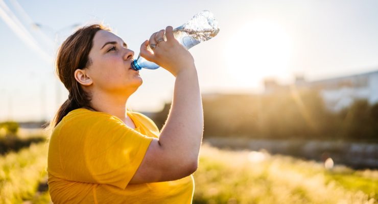 A woman enjoys water during a break on her run outdoors, but is she getting her electrolytes?