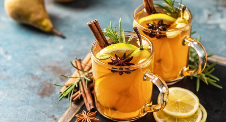 A pair of hot toddies with fresh fruit and cinnamon