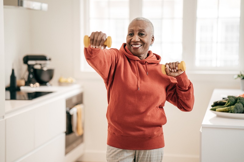 Smiling woman doing arm exercises with hand weights