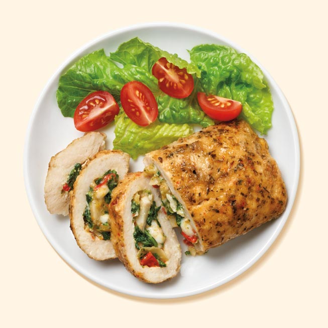 A plate of chicken breast stuffed with artichoke and spinach with a side of salad