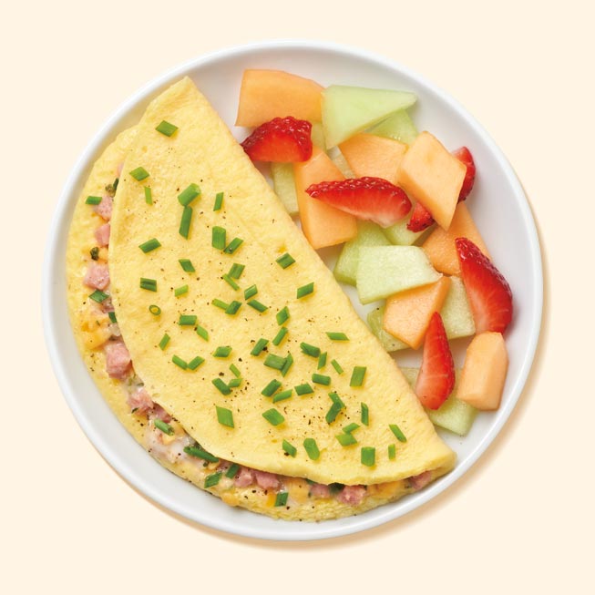 Turkey ham and cheese omelet on a plate with fruit salad 