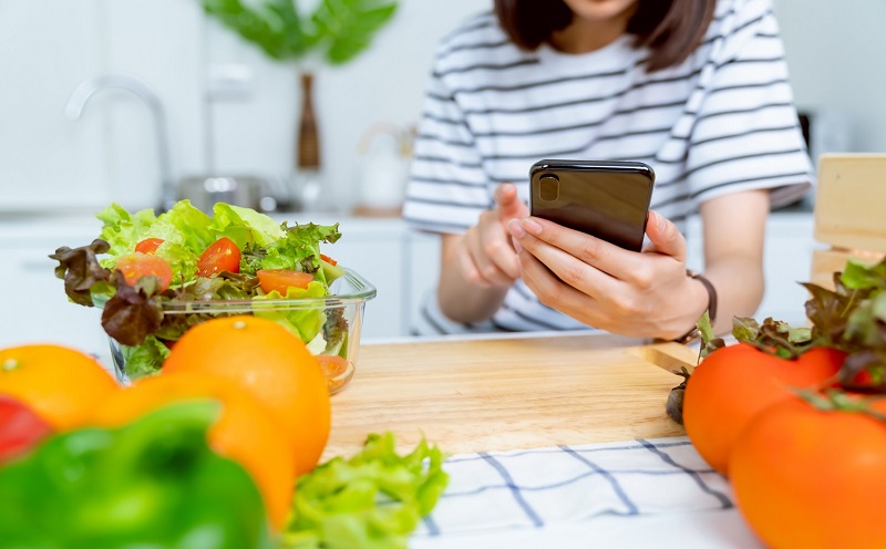 woman on smart phone next to a salad