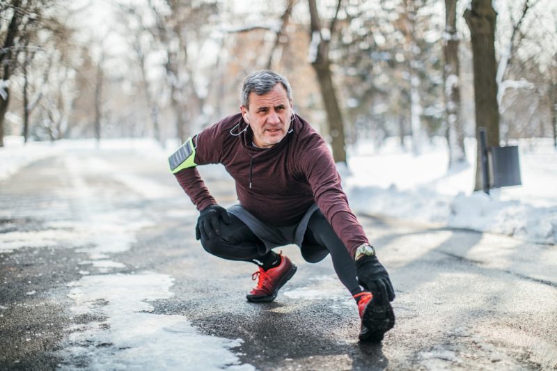 Man stretching hamstring in the snow