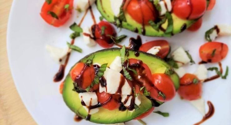 Caprese Stuffed Avocados with tomatoes and mozzarella on a plate drizzled with balsamic glaze