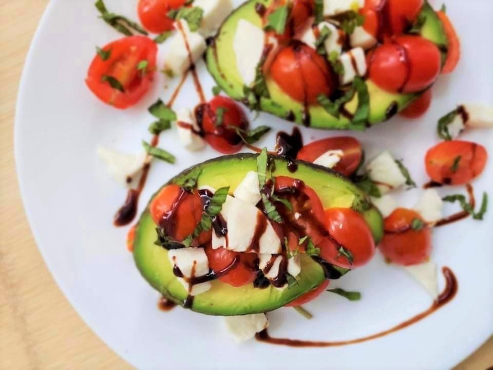 Caprese Stuffed Avocados with tomatoes and mozzarella on a plate drizzled with balsamic glaze