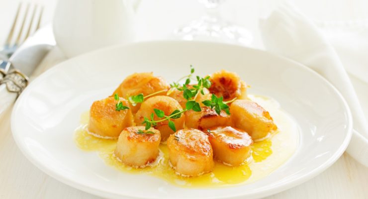 pan seared scallops on a plate with fresh herbs