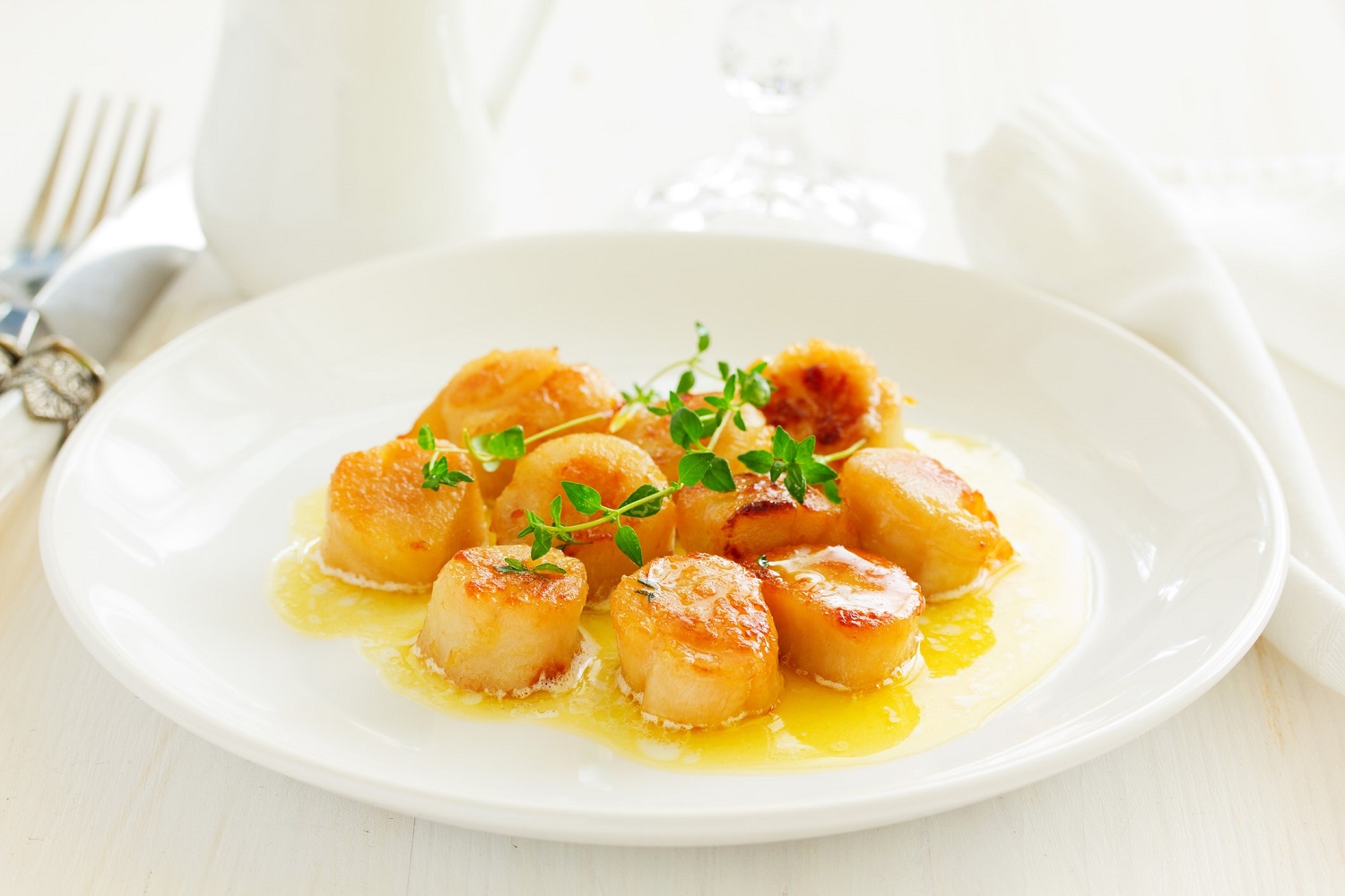 pan seared scallops on a plate with fresh herbs