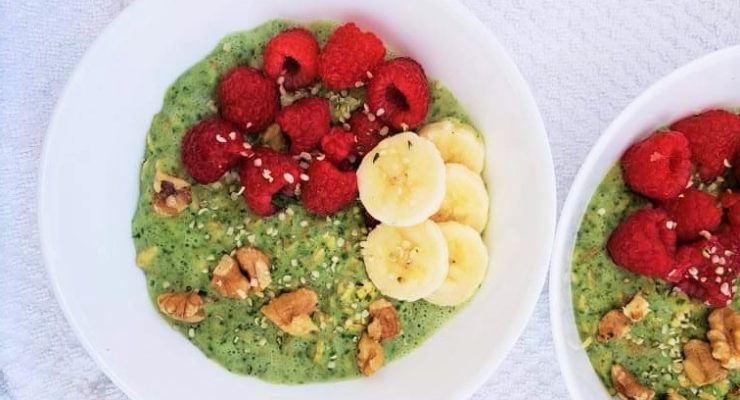 Green Protein Powder Oatmeal Bowl topped with banana slices, raspberries and walnuts