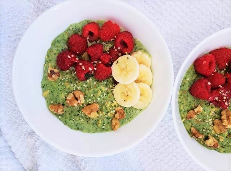 Green Protein Powder Oatmeal Bowl topped with banana slices, raspberries and walnuts