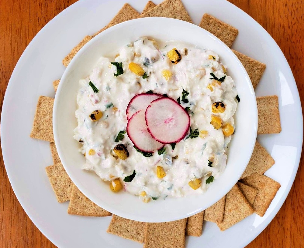 Creamy Radish Feta Dip in a bowl with corn and whole grain crackers