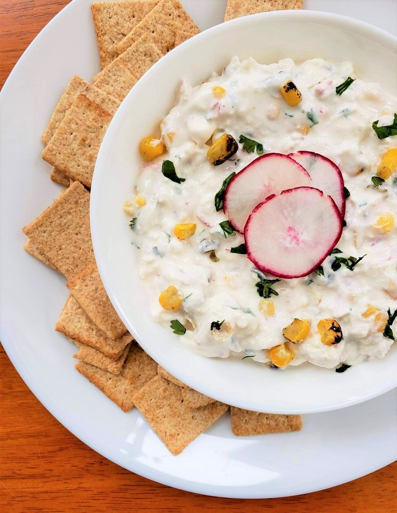 Creamy Radish Feta Dip in a bowl with corn and whole grain crackers