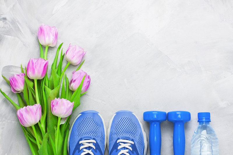 spring flowers next to sneakers, dumbbells and a water bottle