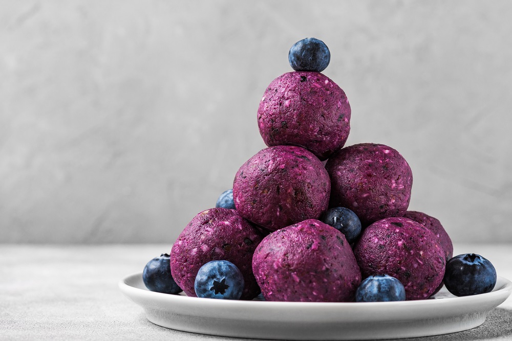 blueberry acai energy balls on a plate with blueberries