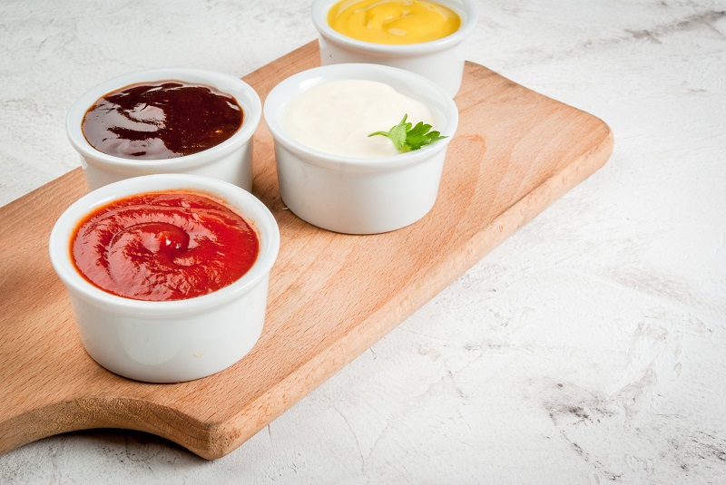 assorted condiments for grilling in white bowls