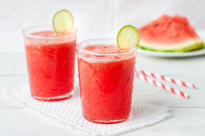 Two watermelon drinks with lime garnish 