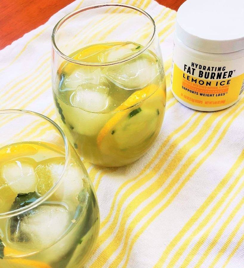 Nutrisystem Lemon Ice Hydrating Fat Burner next to two glasses of lemon drink with fresh mint and ice on a striped yellow towel