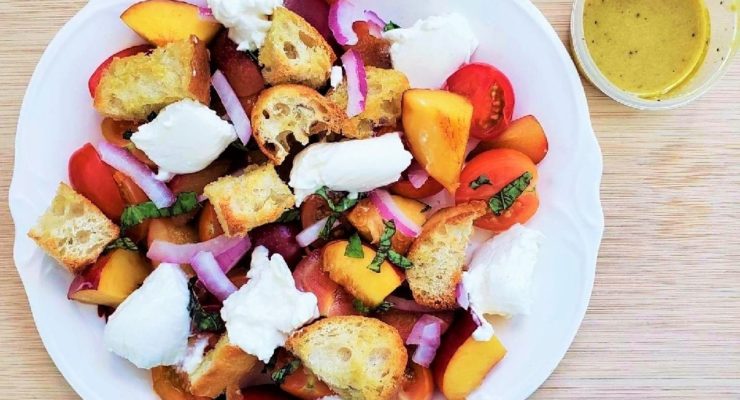 Colorful Summer Panzanella Salad on a white plate with a side of homemade salad dressing